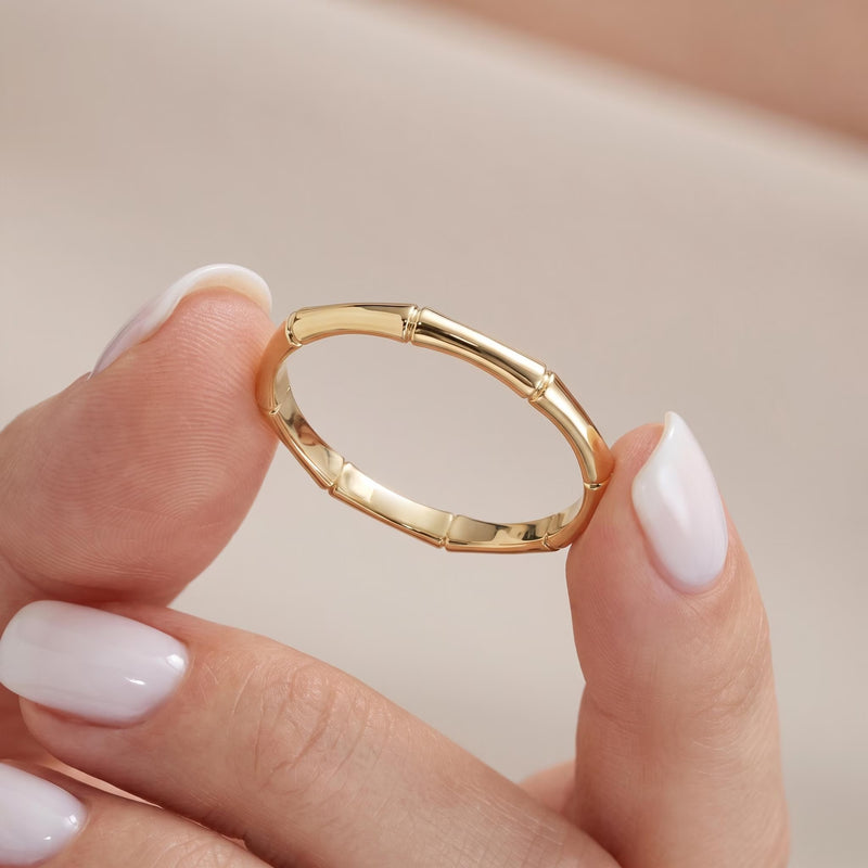 Solid gold bamboo ring held between fingers