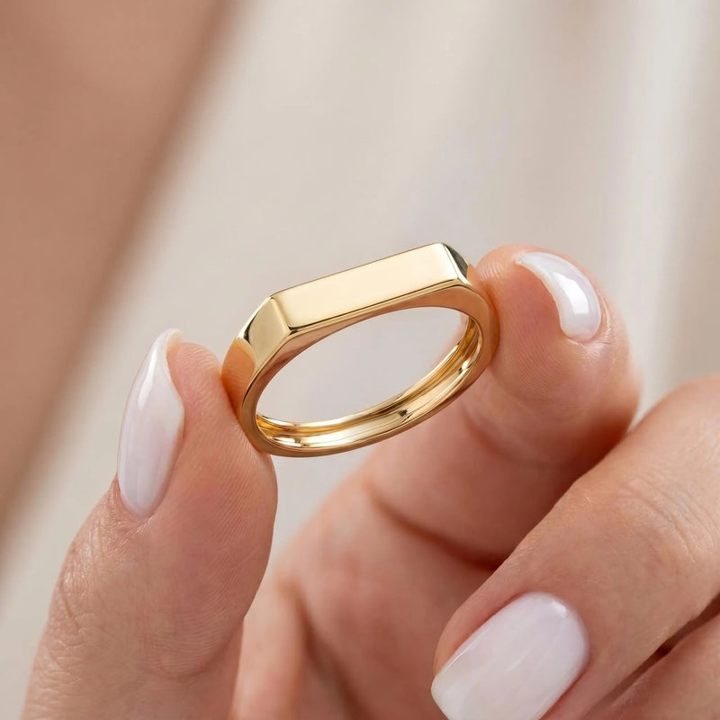 Solid gold bar signet ring held between fingers