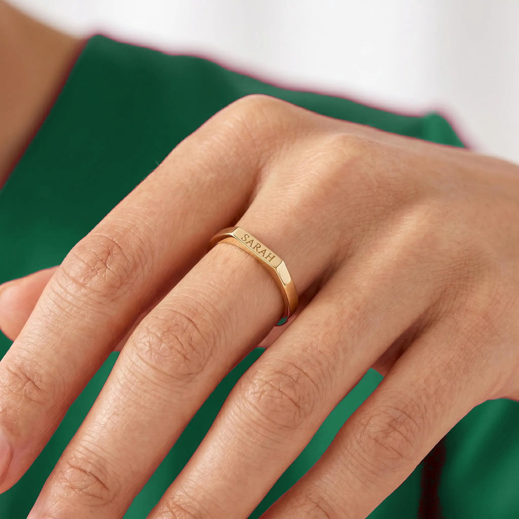 Engraved gold bar signet ring worn on finger