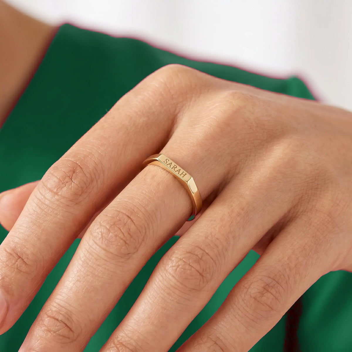 Engraved gold bar signet ring worn on finger