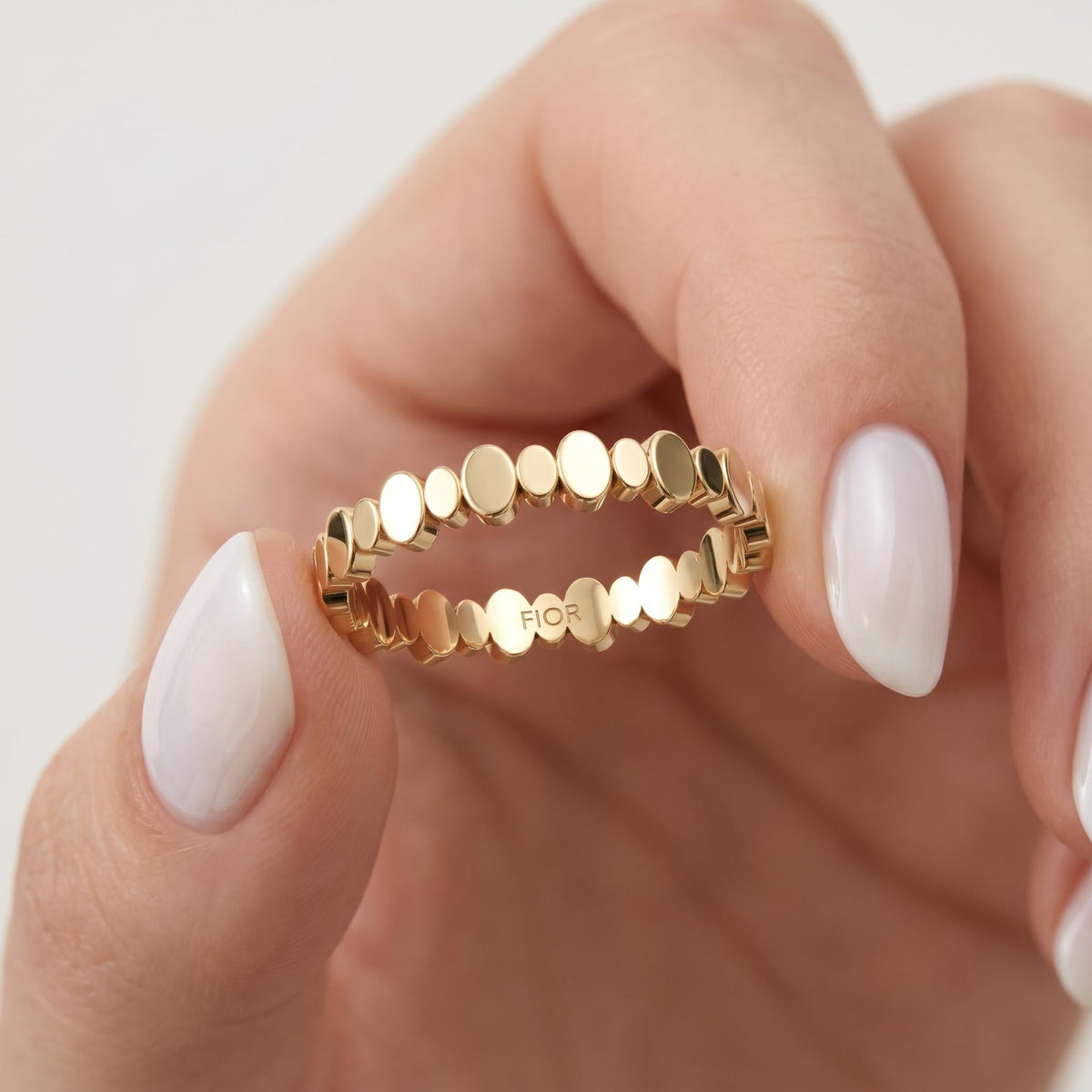 Beaded gold ring held between fingers