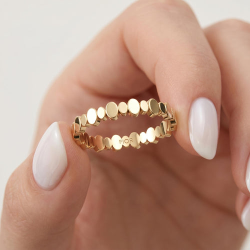 Beaded gold ring held between fingers
