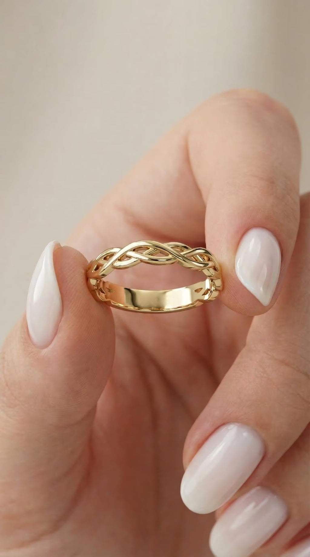 Solid gold Celtic knot ring held between fingers