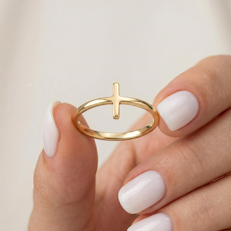 Solid gold vertical cross ring held between fingers