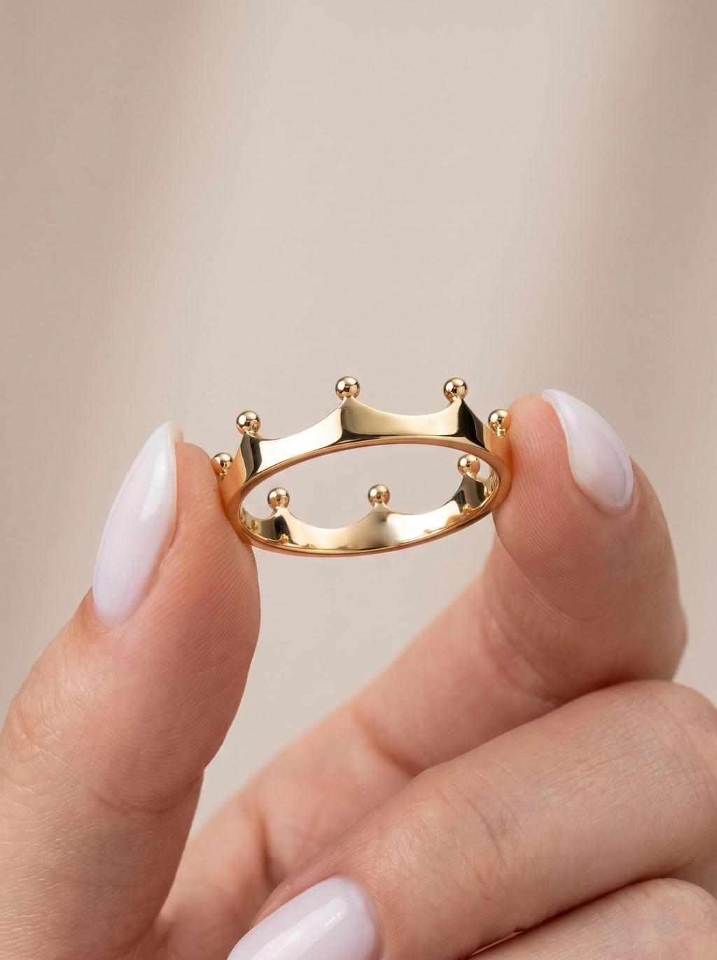 Solid gold crown ring held between fingers