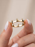 Solid gold crown ring held between fingers