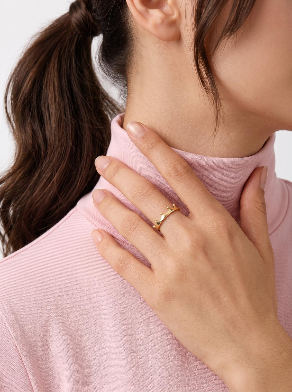 Gold crown ring worn near neckline