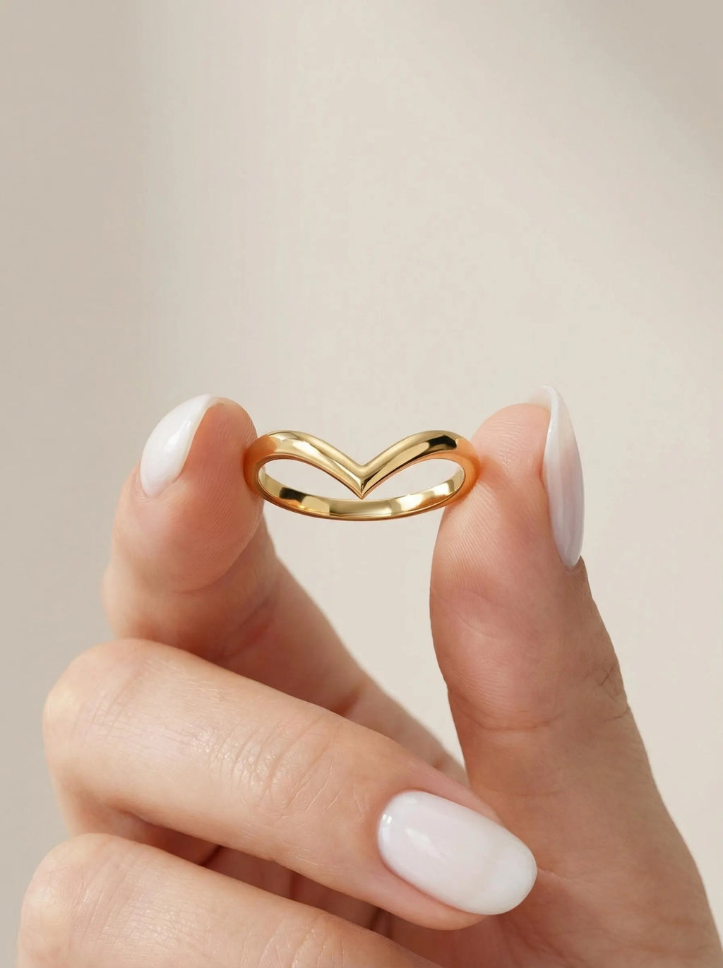 Curved chevron wedding band held between fingers