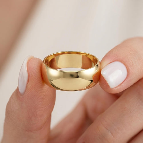 Yellow gold dome band held between fingers