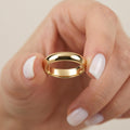 Solid gold 4mm dome wedding band held between fingers