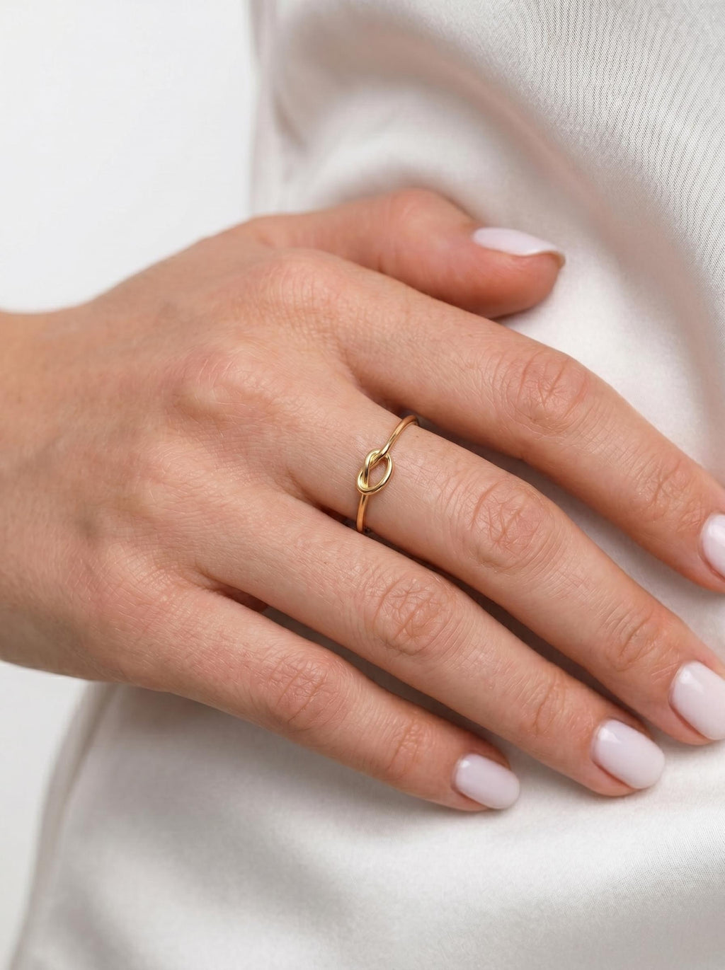 Dainty gold knot ring worn on the hand