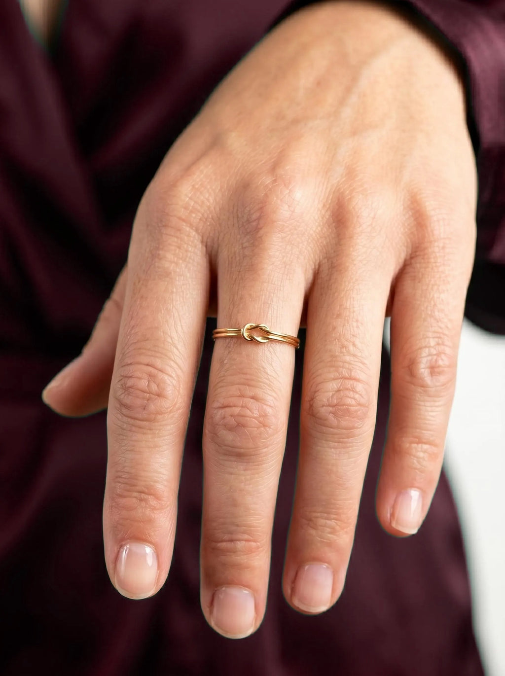 Dainty gold knot ring worn on hand