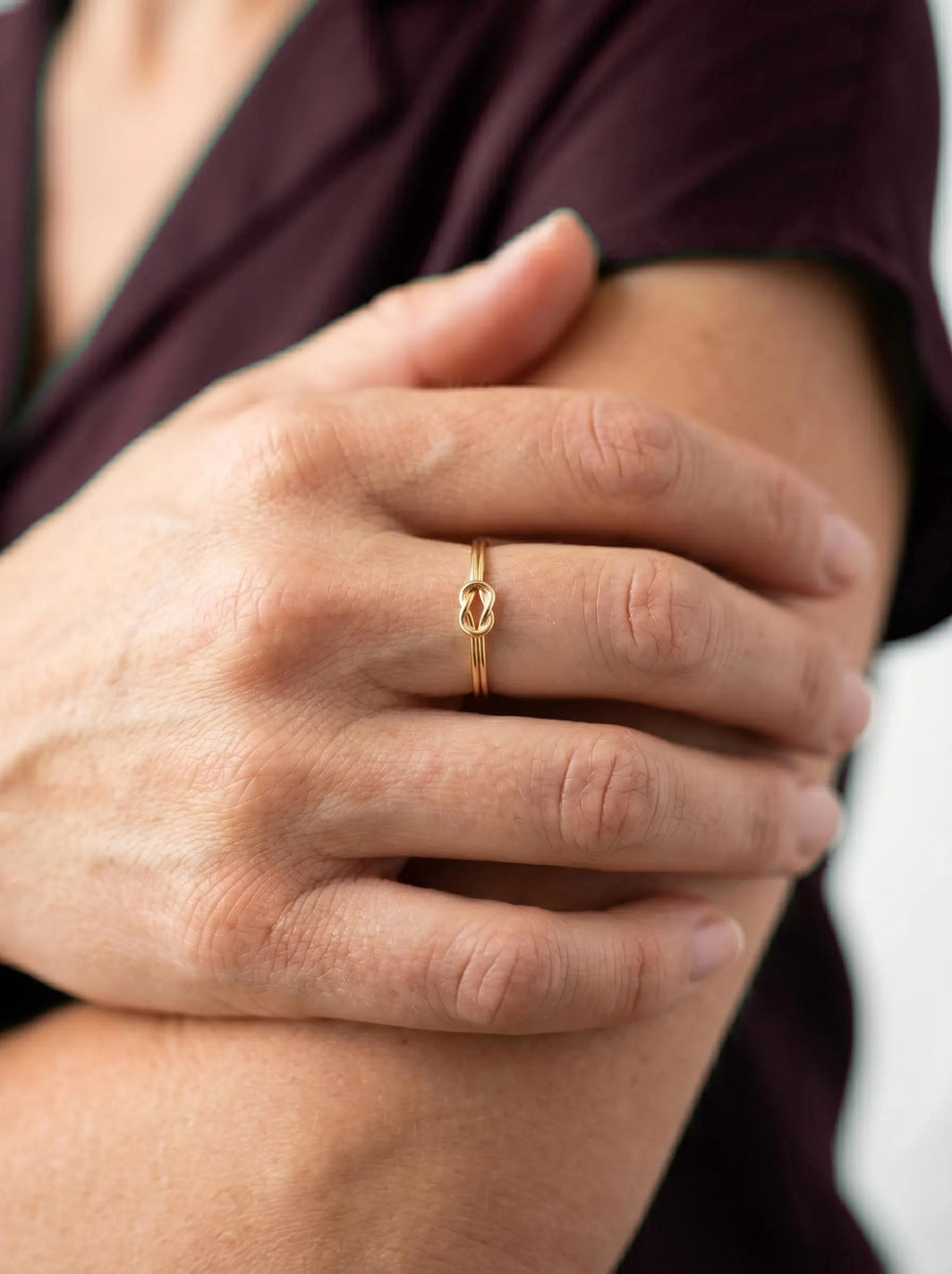 Gold love knot stacking ring on finger