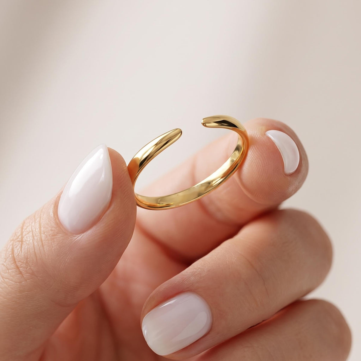 Gold open cuff ring held between fingers