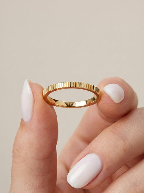 Ribbed gold band held between fingers
