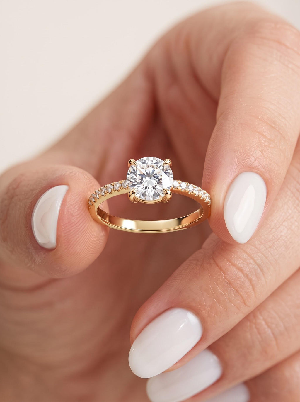 Round lab-grown diamond engagement ring in solid gold held between fingertips