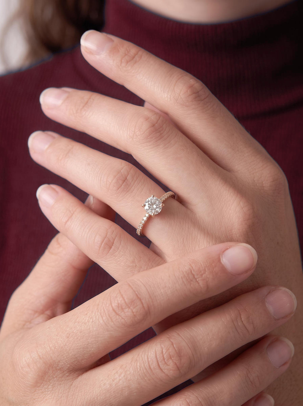 Close-up of the round diamond engagement ring worn on the finger