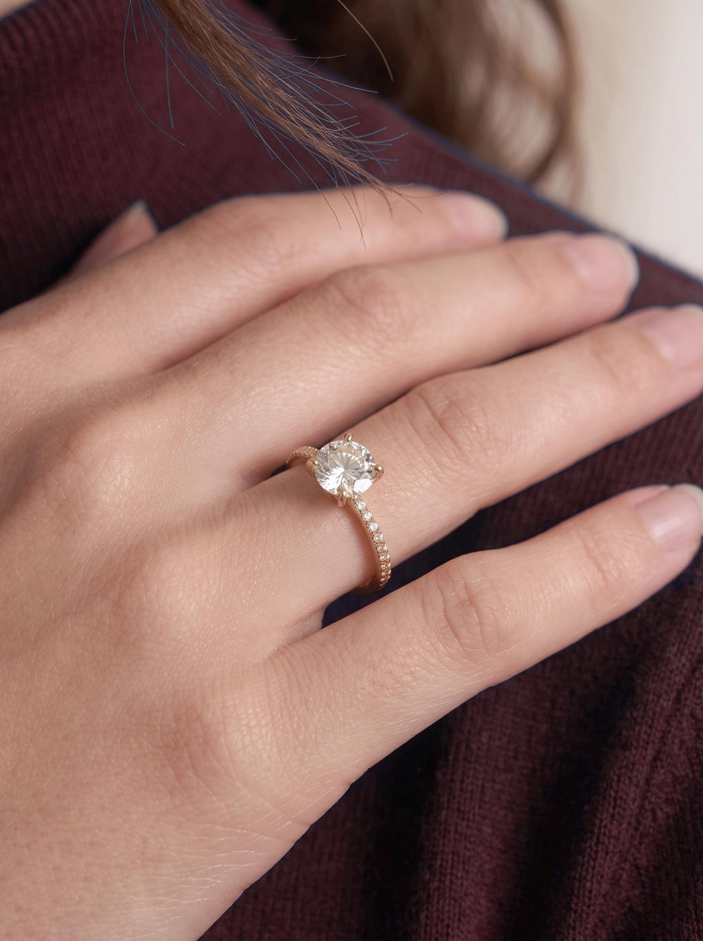 Round diamond engagement ring worn on the hand, close-up