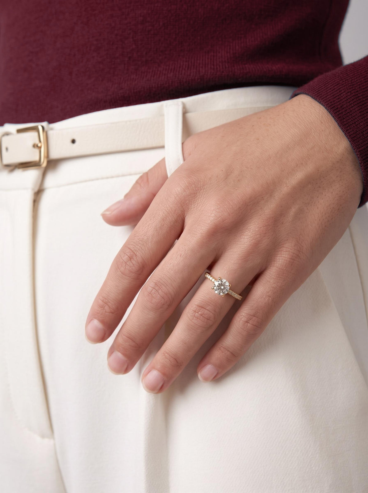 Diamond engagement ring worn with cream trousers
